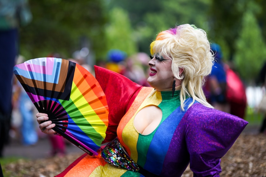 A drag queen dressed in a rainbow outfit