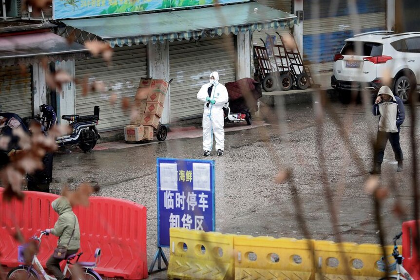 A worker in a protective suit walking through a closed seafood market