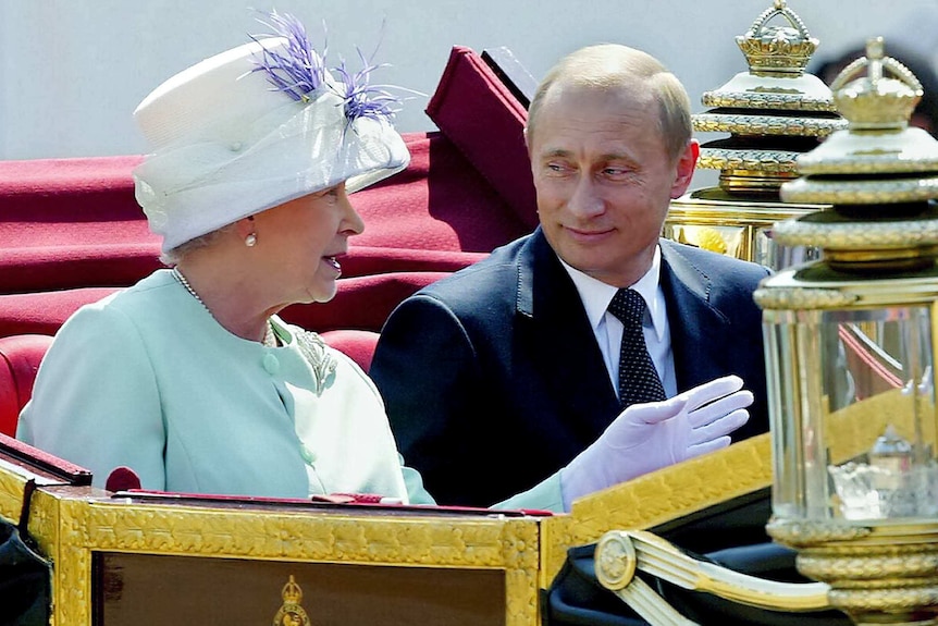 Russian President Vladimir Putin (R) and Queen Elizabeth II ride in an open carriage.