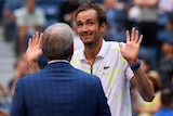 A tennis player holds his hands up to the crowd as he is interviewed after a win at the US Open.