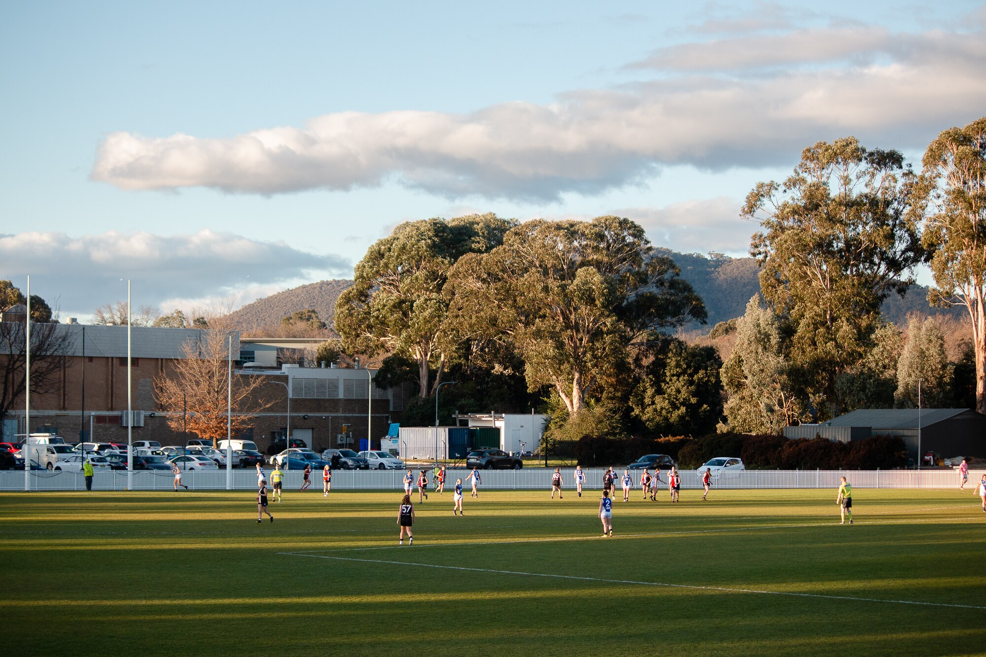 A wide shot of women playing Aussie rules on an oval.