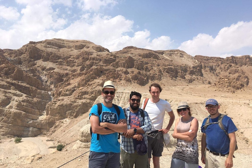 group of adults in casual wear posing amongst desert rocks.