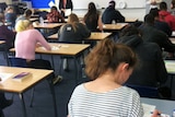 VCE students sit in a classroom with their backs to the camera.