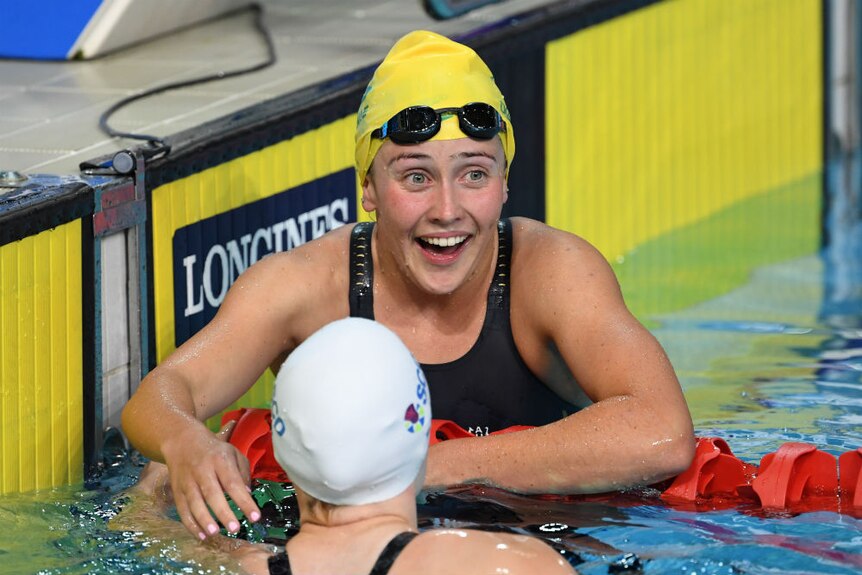 Katherine Downie laughs in the pool after winning a bronze medal.