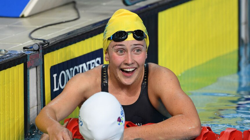 Katherine Downie laughs in the pool after winning a bronze medal.