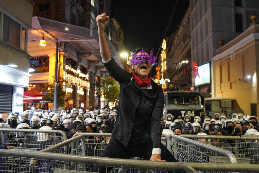 A woman shouts slogans atop a police security barrier.
