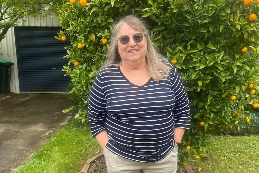 A middle-aged woman standing in front of a lemon tree