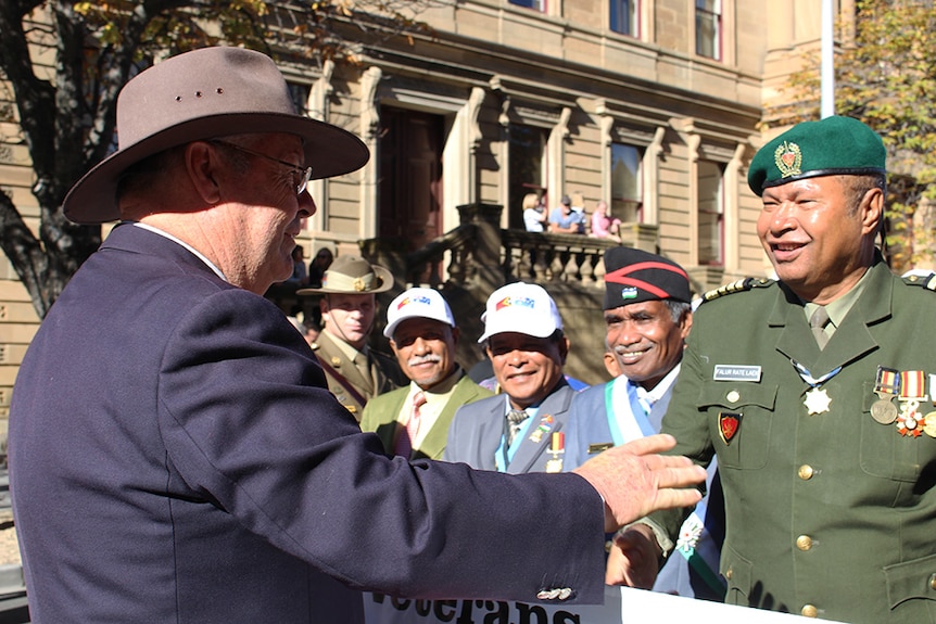 An Australian veteran shakes the hand of East Timorese soldier