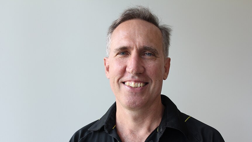 Steve manning standing in front of a white wall.