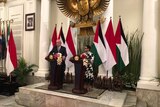 Indonesian Foreign Minister Riyad al-Maliki stands on podium making announcement
