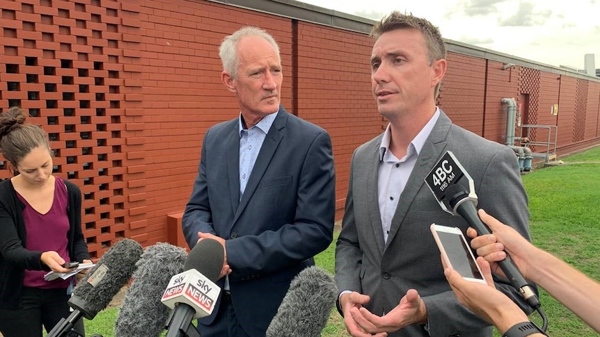 Steve Dickson looks at James Ashby as he speaks. A number of microphones and recording devices are in front of him.