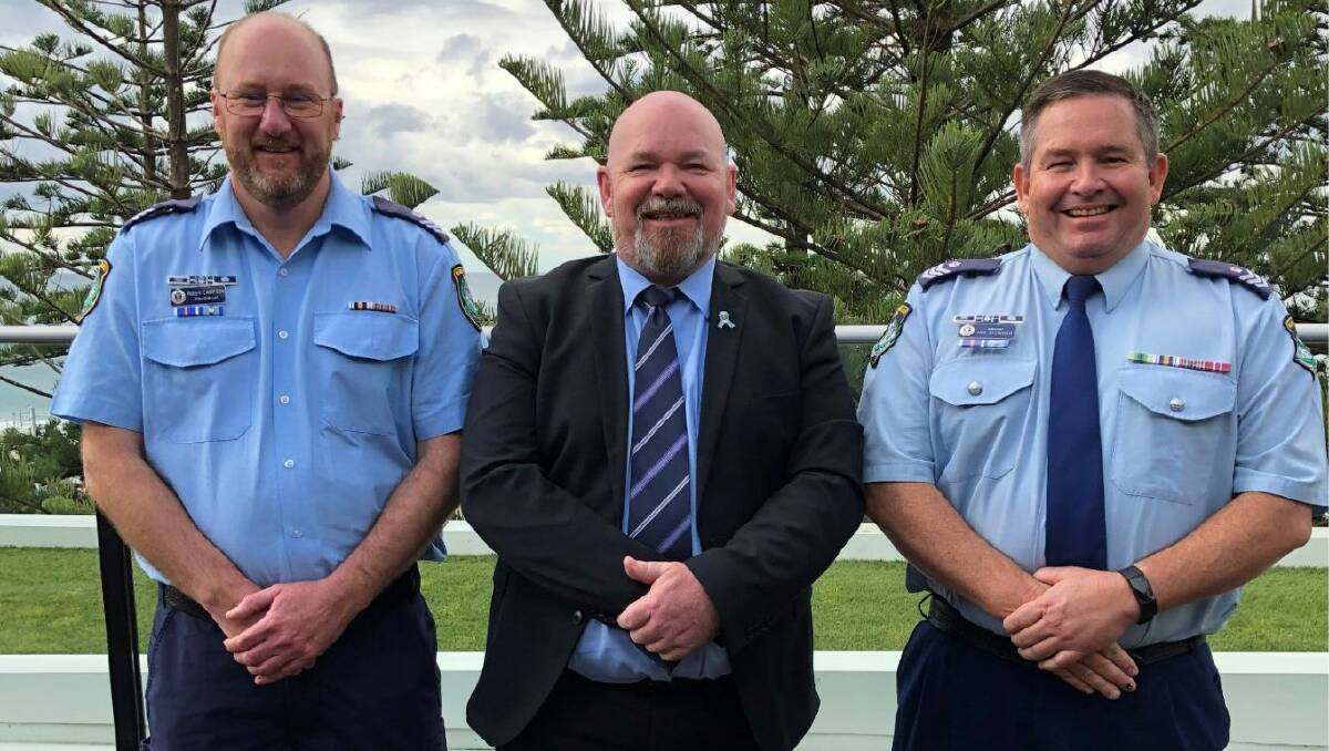 three police officers standing together smiling with hands placed in front of them