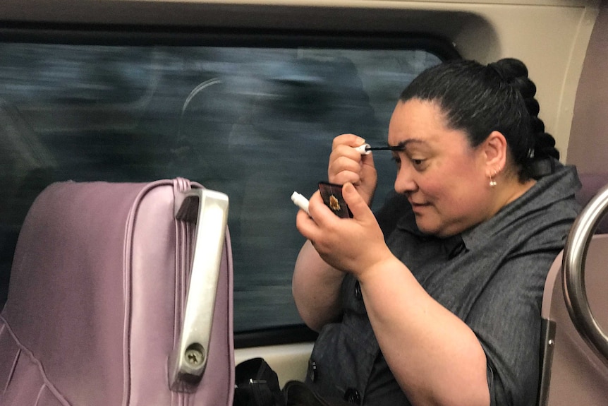 Ellen McCabe does her makeup as she travels into the city.