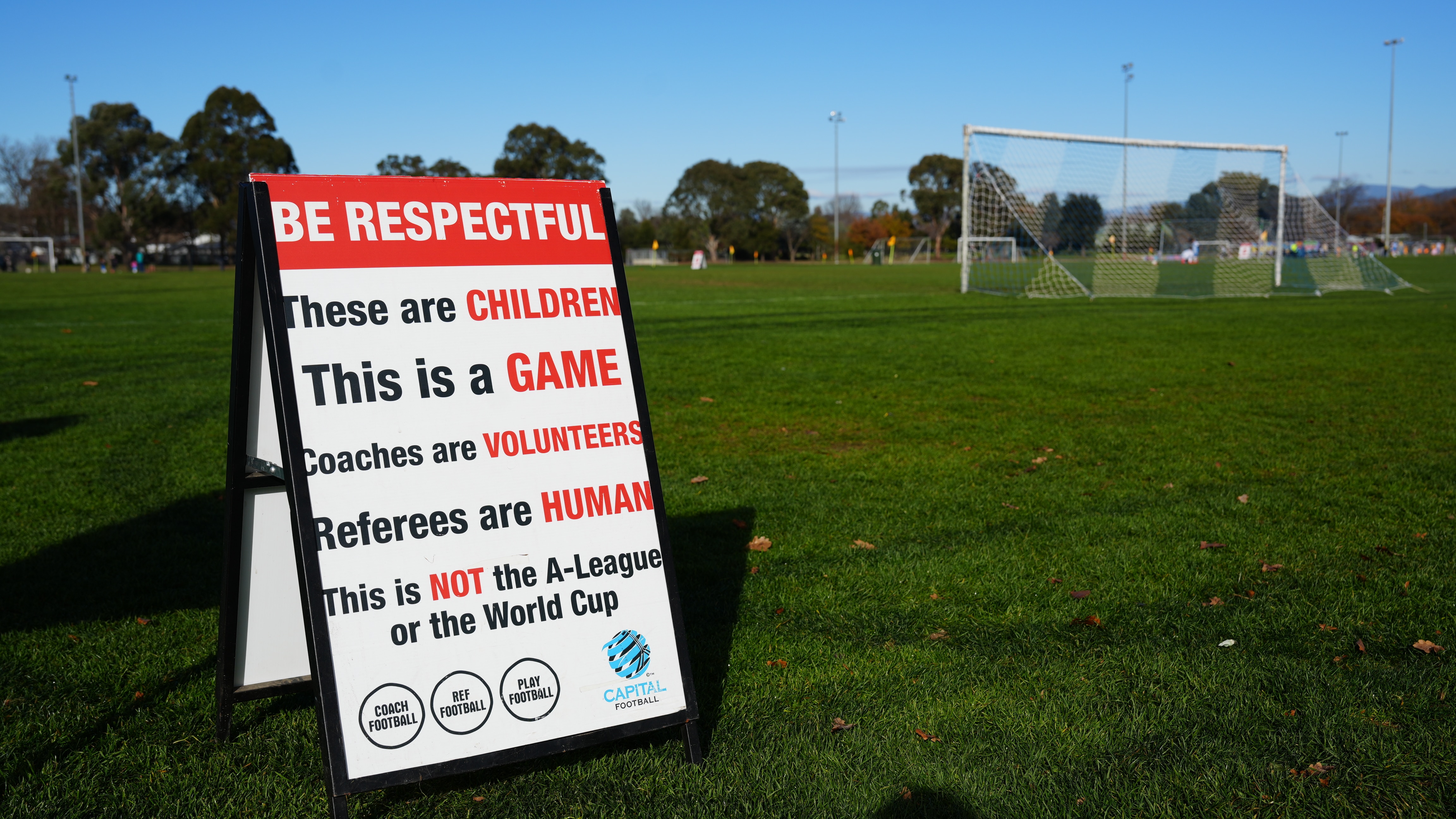 A sign on a soccer field "Be respectful. These are children. This is a game. Coaches are volunteers. Referees are human".