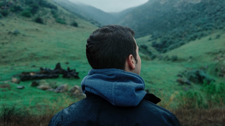 A man looks out at mountains