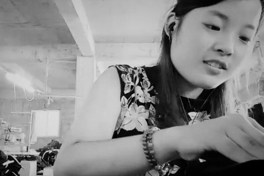 Black and white close-up still of a garment factory worker in 2019 documentary Present.Perfect.