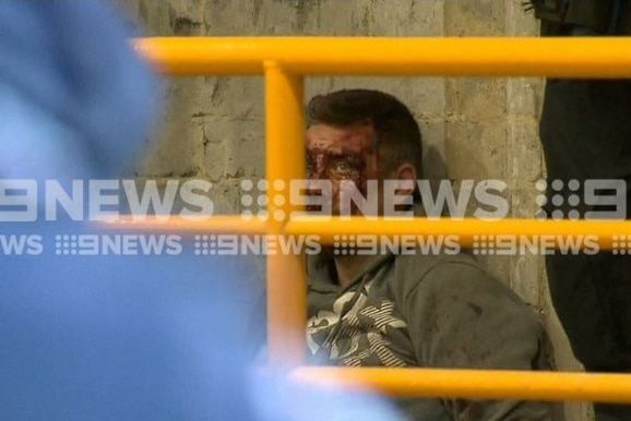 9 News footage showing a man with a bloody face being arrested in a car park.