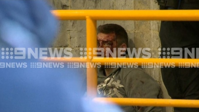 9 News footage showing a man with a bloody face being arrested in a car park.