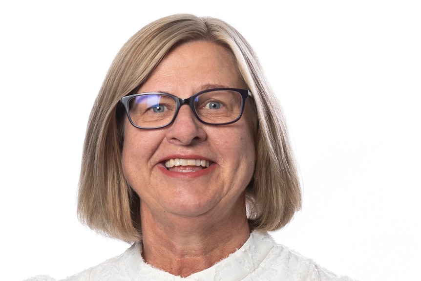 A woman with blond hair and dark glasses smiling for a portrait photo. 