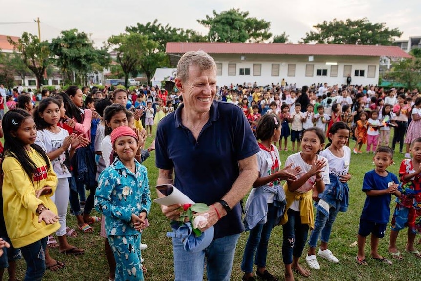 Scott Neeson smiles while walking through a crowd of children
