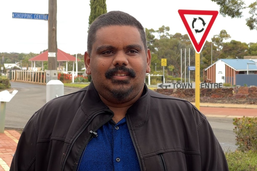 He stands near the town roundabout in a black jacket and dark blue shirt