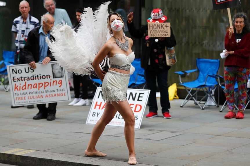 A dancer with a feather tail and heavy silver jewellery performs in protest opposite the Central Criminal Court.
