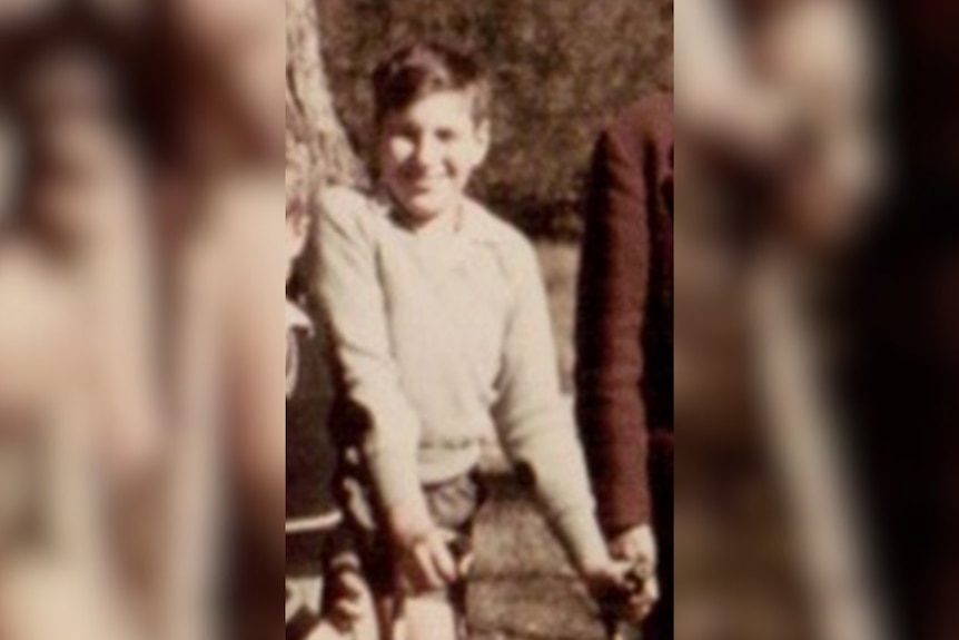 An old sepia photo of a young boy using crutches