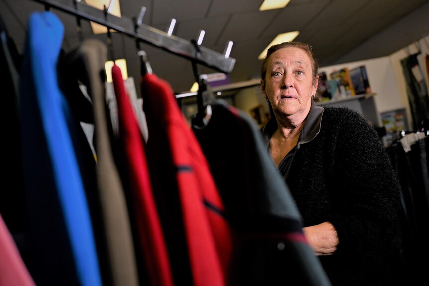 A woman next to a rack of clothes