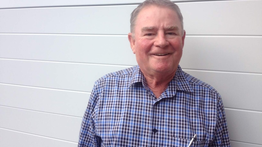 Man in blue checked shirt smiles at camera