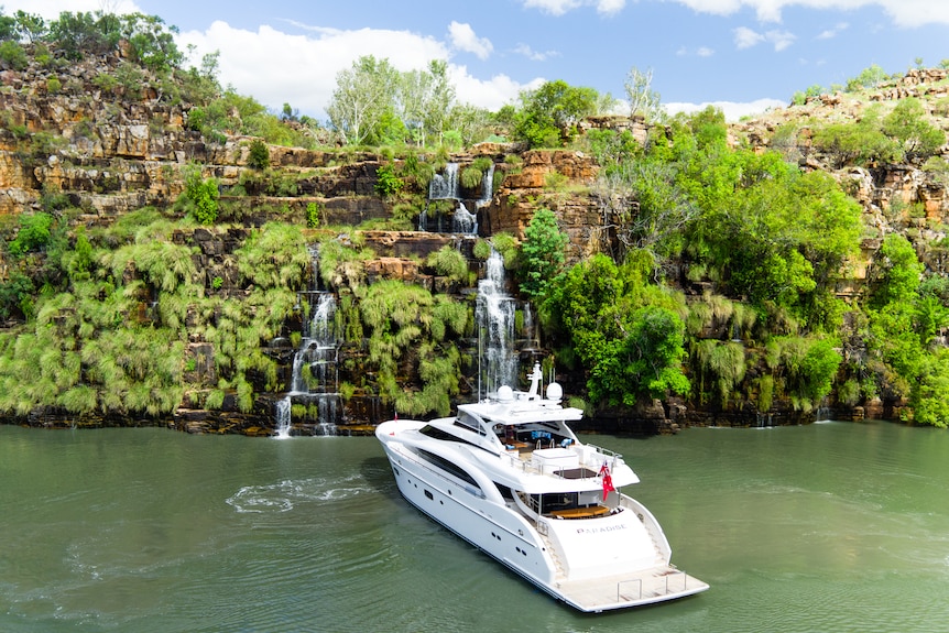 A super yacht sits beneath a waterfall
