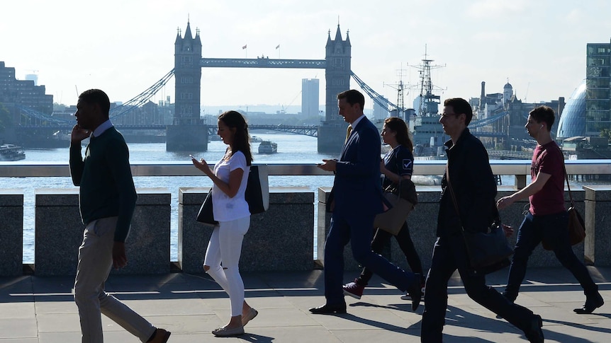 Commuters heading into the City of London cross London Bridge in front of Tower Bridge