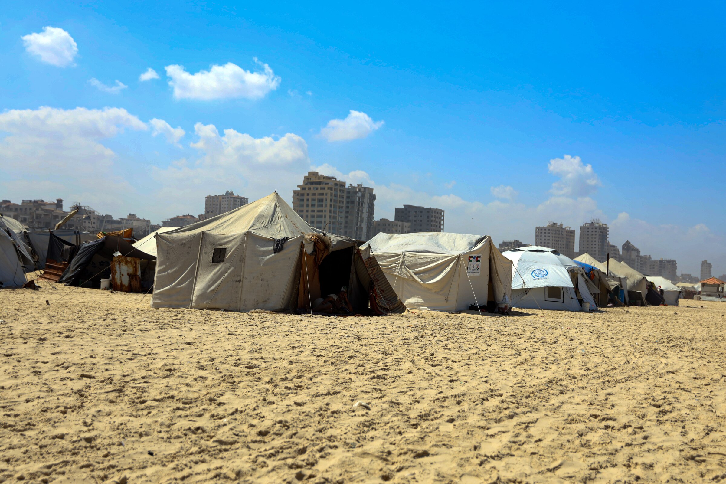 Several makeshift tents pitched on beach sand
