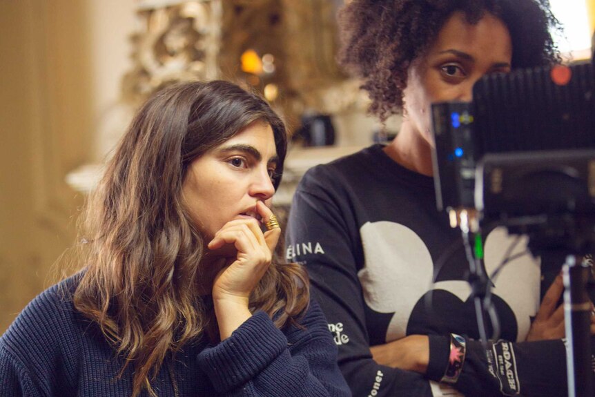 A young woman stares into a camera on a set