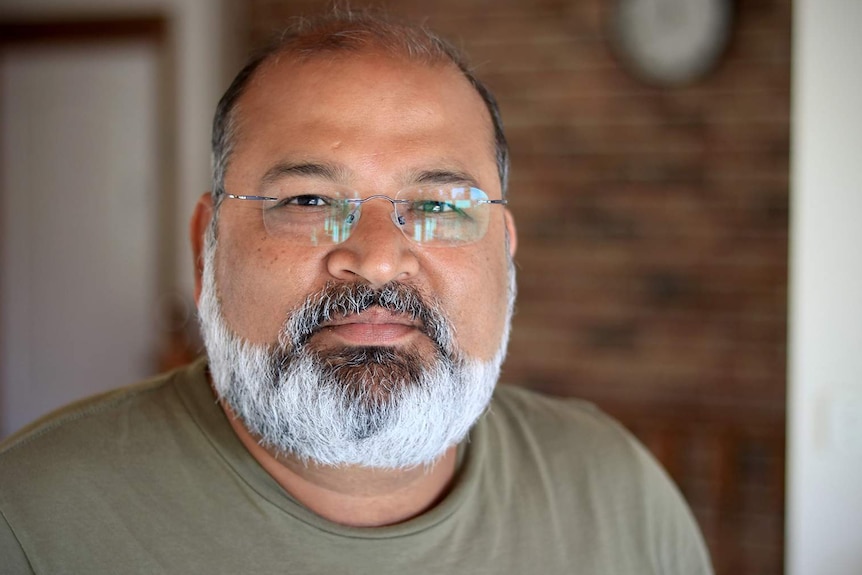 A close up photo of Nav Mittal wearing reading glasses and looking at the camera.