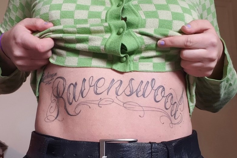 Tattooed midriff daying the word ravenswood in facy lettering 