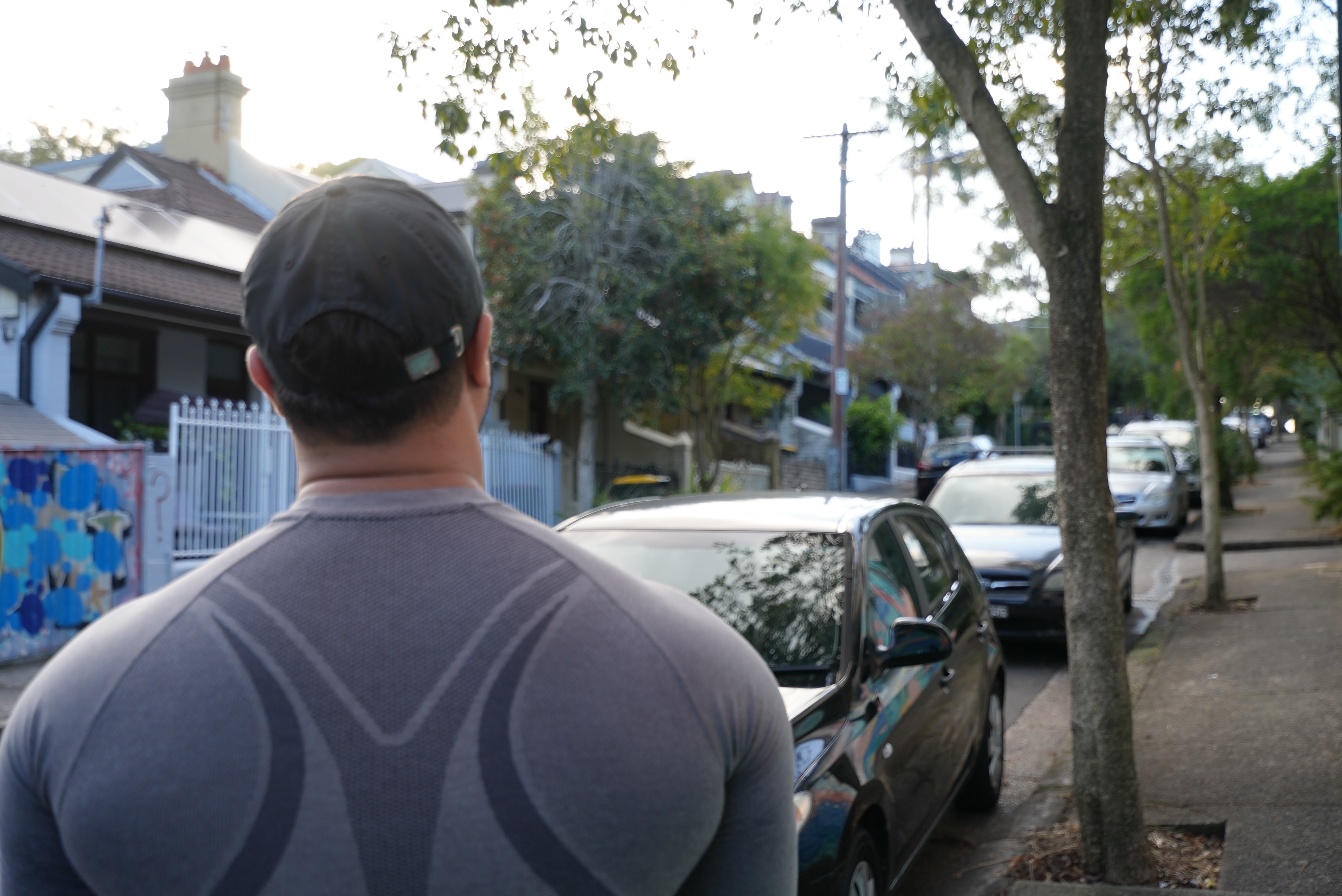 man stands with back to camera looking at streetscape