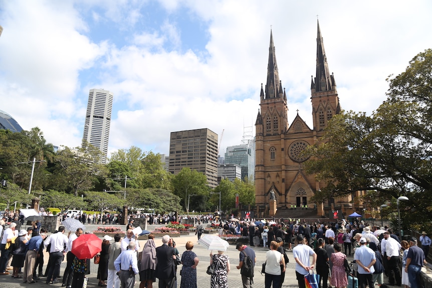 Hundreds of people lined up to get into a cathedral