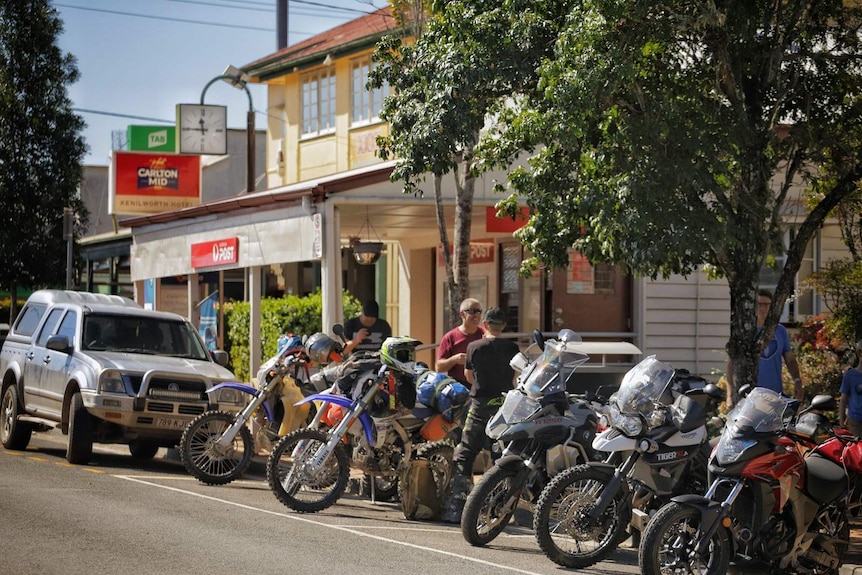 A row of motorcycles parked outside a country convenience store