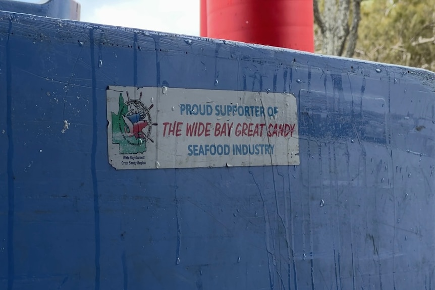 A support local fishermen sticker on a blue bin 