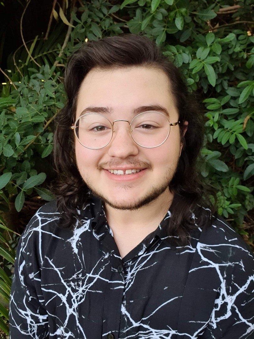 A young man with glasses and shoulder length brown hair