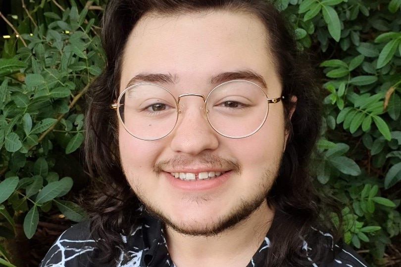 A young man with glasses and shoulder length brown hair