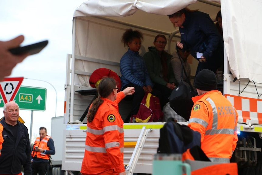 A group of SES volunteers helping people out of a truck