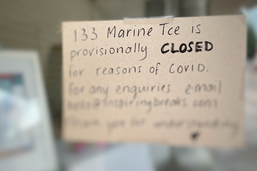 A sign reading "133 Marine Tce is provisionally closed reasons of COVID" is stuck to a window.
