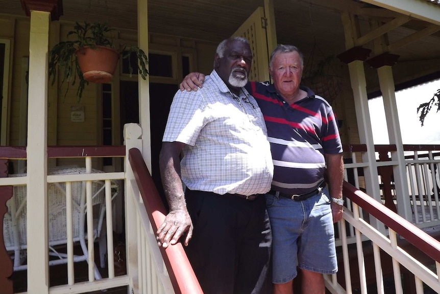 Matt Nagas and Brian Courtice stand on steps next to each other outside a house.