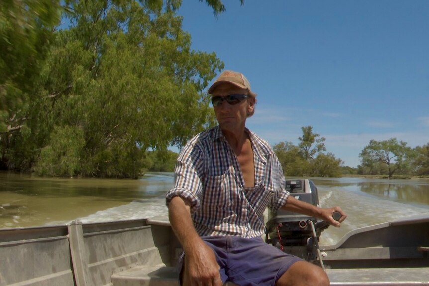Geoff Davies in a boat travelling along the Darling River. 