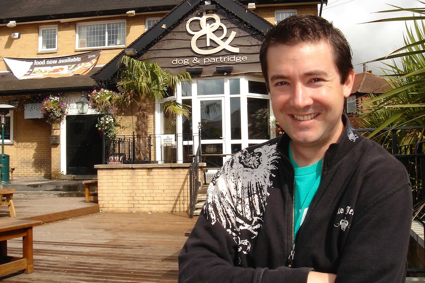 Michael Tetlow stands with his arms crossed outside the Dog and Partridge English pub.