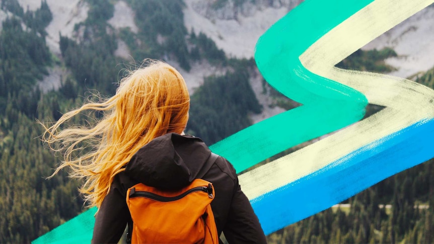Woman with red hair and orange backpack looking toward a mountain range to depict taking a gap year.