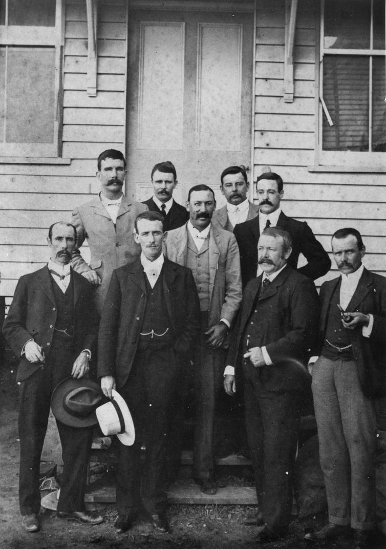 Black and white image of men in suits with hats