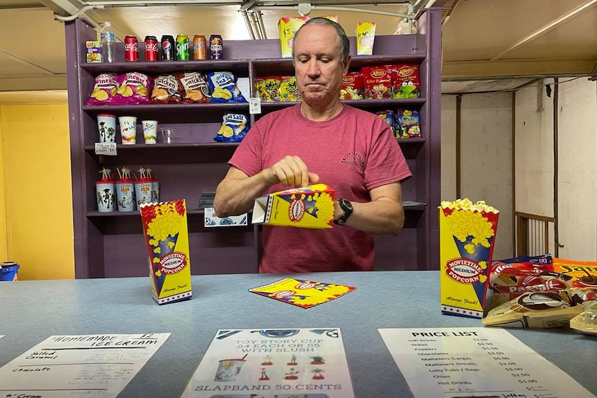 Man putting together popcorn boxes at Candy bar. 