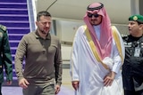 Two men in green army uniforms stand beside President Zelenskyy and a man traditional Arab clothing